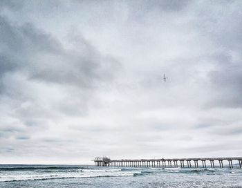 Pier on sea against cloudy sky