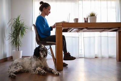 Side view of young man sitting on hardwood floor at home