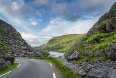 Empty road by mountains against sky