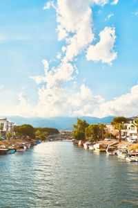 Scenic view of river by buildings against sky