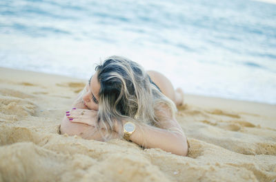 Woman lying down on sand at beach