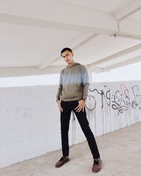 Full length portrait of young man standing against wall