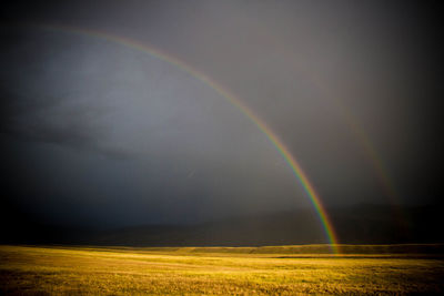 Scenic view of rainbow over field against sky