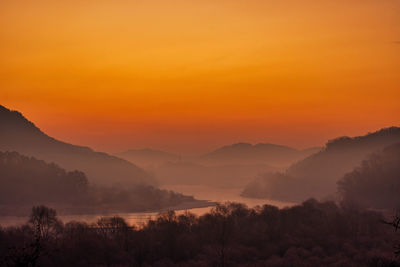 Scenic view of silhouette mountains against the orange sky