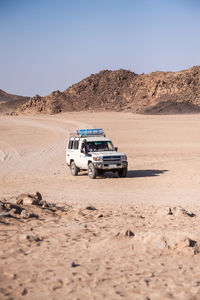 View of car on desert against clear sky