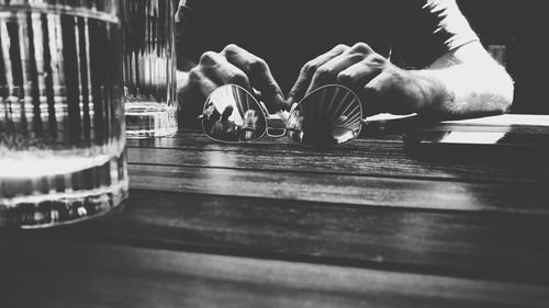 Midsection of man holding sunglass with friend reflecting on table