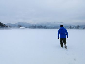 Rear view of man walking on snow covered mountain