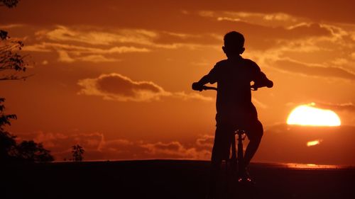 Rear view of silhouette boy against sunset sky