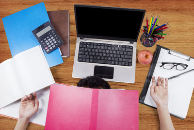 High angle view of frustrated man gesturing over laptop by objects on table