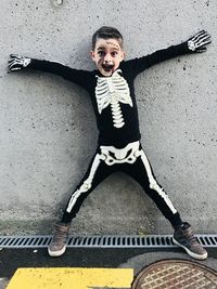 Portrait  of boy in halloween costume standing against wall