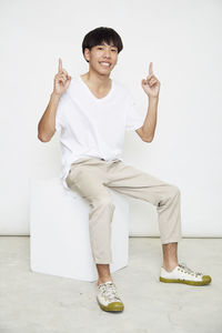 Portrait of smiling young man standing against white background