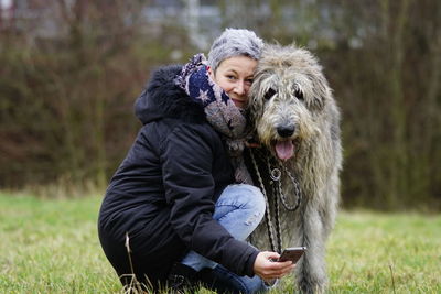 Portrait of woman with irish wolfhound sitting on grass