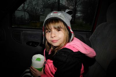 Portrait of girl holding bottle in car