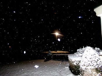 Close-up of illuminated snow against sky at night