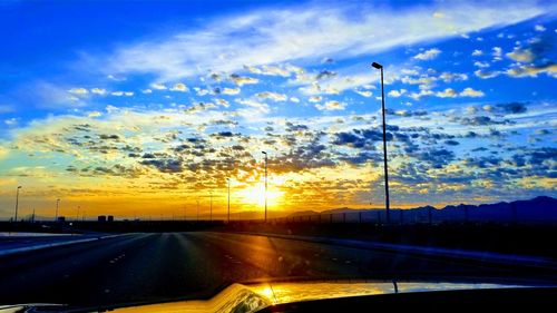 Road amidst silhouette trees against sky during sunset