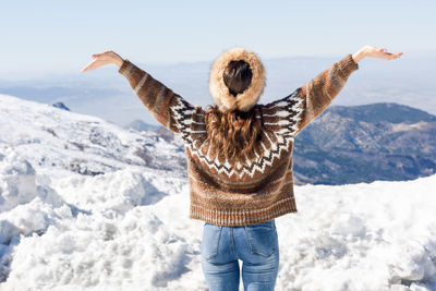 Rear view of woman standing on snow covered mountain