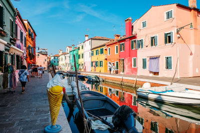 Boats in canal amidst buildings in city against sky