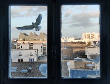 View of cityscape against sky seen through window