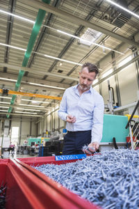 Man in factory examining shred in container