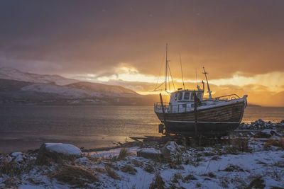 Norwegian wooden boat beached at sunset with snow