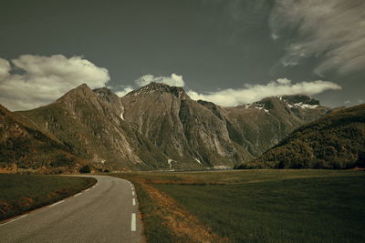 Country road amidst mountains against sky
