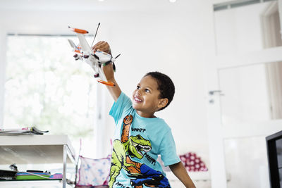 Boy holding toy while standing at home