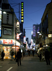 People walking on illuminated street at night