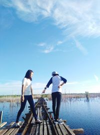 People standing by lake against sky