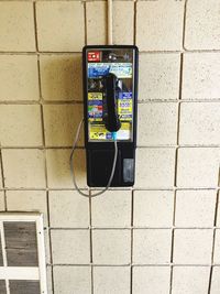 Close-up of telephone booth on brick wall