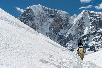 Rear view of person on snowcapped mountains against sky