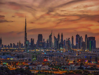 Illuminated cityscape against sky during sunset