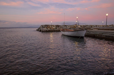 Sailboat moored on sea against sky during sunset