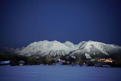 Scenic view of snowcapped mountains against clear blue sky at night