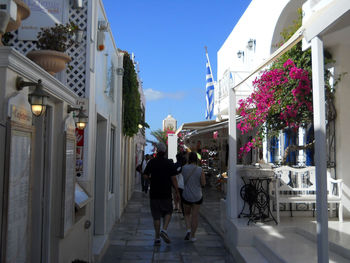 Rear view of people walking on sidewalk in city