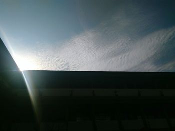 Low angle view of sun shining through clouds