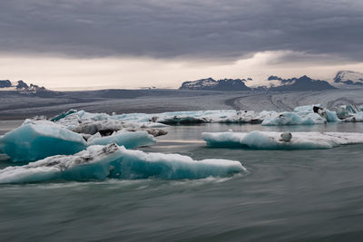 Scenic view of icebergs in sea against sky