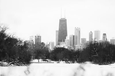 Trees and buildings against sky during winter