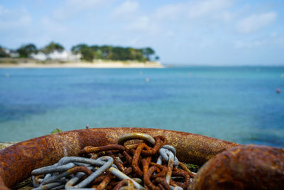 Close-up of rusty metal on beach against sky