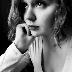 Close-up of beautiful young woman against black background