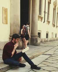 Young couple sitting on sidewalk in city