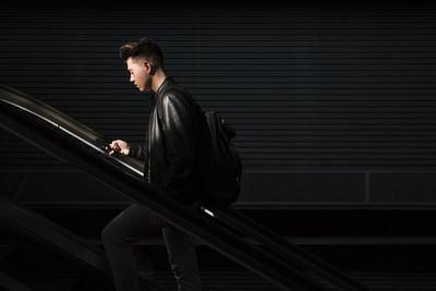 Man using smart phone on escalator