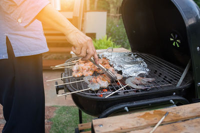 Mid section of a woman preparing food on barbecue grill