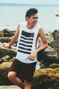 Young man standing on rock at beach