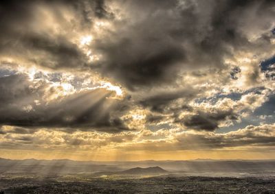 Sunlight streaming through clouds over landscape
