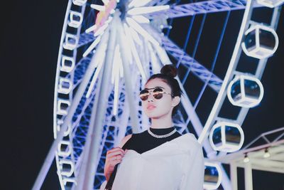 Low angle view of young woman against ferris wheel