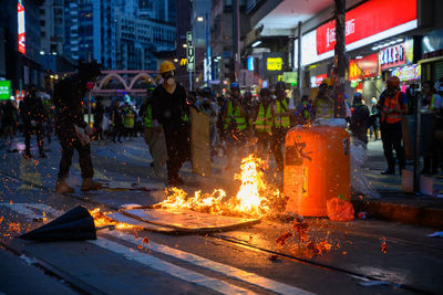 People on illuminated street in city at night