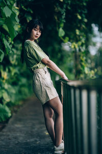 Young woman standing against trees