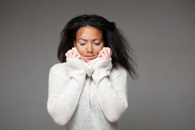 Portrait of young woman standing against wall