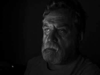 Close-up of serious senior man against black background