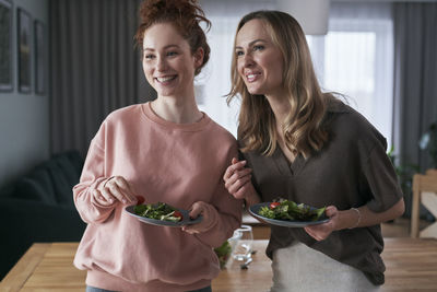 Smiling friends eating food while talking